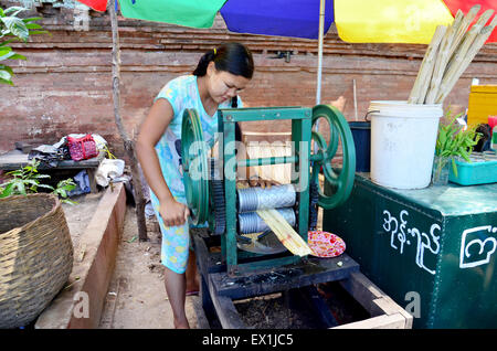 Fille birmane fait jus de canne à sucre par bouilloire machine manuelle à vendre à voyageur Htilominlo Temple de Bagan, Myanmar. Banque D'Images