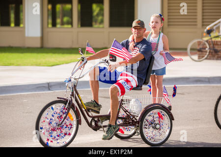 La Caroline du Sud, USA. 4 juillet, 2015. Un père et sa fille ride passé sur un tricycle décoré de banderoles et drapeaux américains au cours de l'indépendance de l'Île Sullivan's Day Parade le 4 juillet 2015 à Sullivan's Island, Caroline du Sud. Banque D'Images