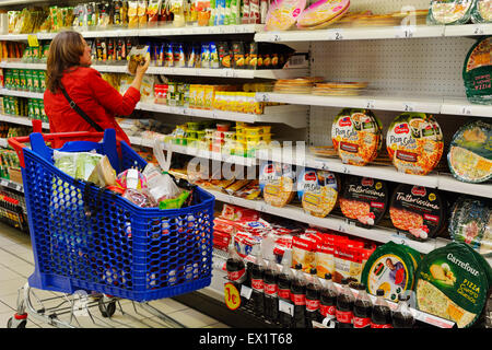 Woman shopping in supermarket qui étagères de pizza et autres aliments emballés Banque D'Images