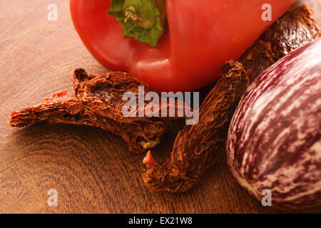 Tomates séchées au soleil, poivrons et aubergines sur une planche à découper en bois. Banque D'Images