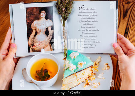 Lisez le livre de gâteaux thé popcorn mains lecture turquoise Banque D'Images