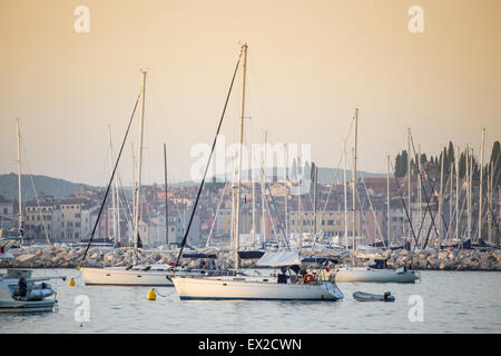 RSailboats ancrée dans la mer Adriatique près de la côte avec vue sur le clocher de Saint Euphémie au coucher du soleil à Rovinj, Croatie Banque D'Images