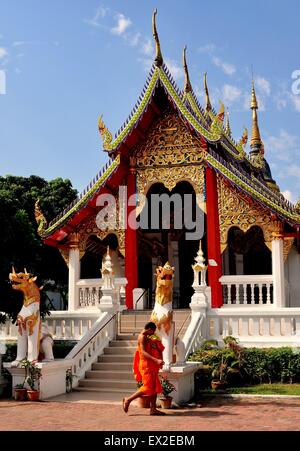 Chiang Mai, Thaïlande : Le moine bouddhiste en robe orange passe devant l'opulent le nord de style Lanna Vihan hall at Wat Pan Ping Banque D'Images