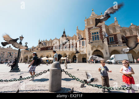 Cracovie, Pologne - mai, 16, 2013 Nos gens au carré central en face de la Halle. Les enfants se nourrissent des colombes derrière la chaîne. Belle fil Banque D'Images