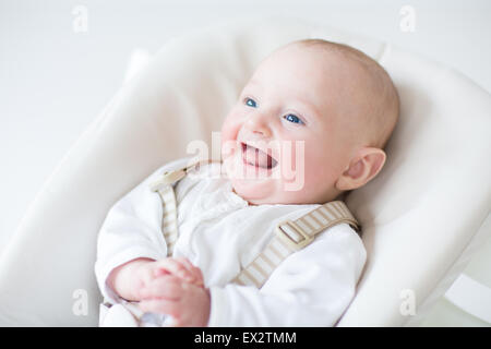 Rires de bébé mignon garçon assis sur une chaise haute en attente pour le déjeuner Banque D'Images