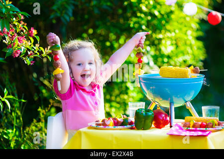 Les enfants de la viande cuisson. Camping en famille et profiter du barbecue. Petite fille à préparer un barbecue biftecks, brochettes et le maïs. Banque D'Images