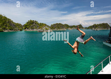 Un jeune homme fait un tableau d'un bateau en Fam de Raja Ampat Islands. Banque D'Images