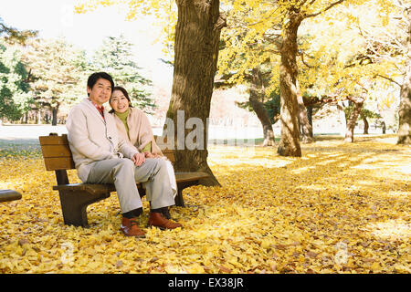La haute couple japonais assis sur un banc dans un parc de la ville Banque D'Images