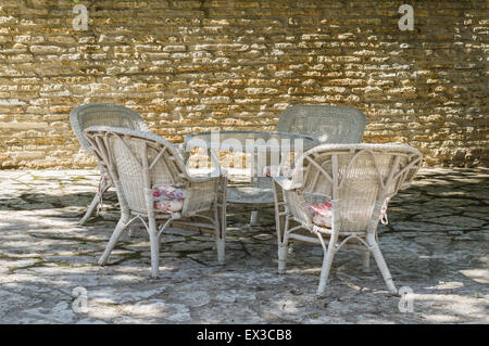 Terrasse extérieure au mur de calcaire, cour avec mobilier chaise en rotin Banque D'Images