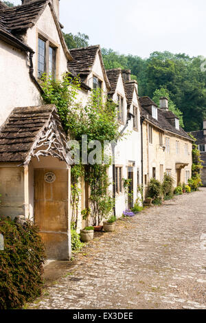 Vieux village de Cotswold monde Castle Coombe, Somerset, Angleterre. Chemin non goudronné passé en courant une rangée de maisons en pierre dans une scène pittoresque. Banque D'Images