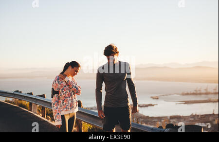 Tourné en plein air de deux jeunes personnes prenant une pause après l'exécution d'une séance de formation. L'homme et la femme debout près d'une balustrade on hillside Banque D'Images