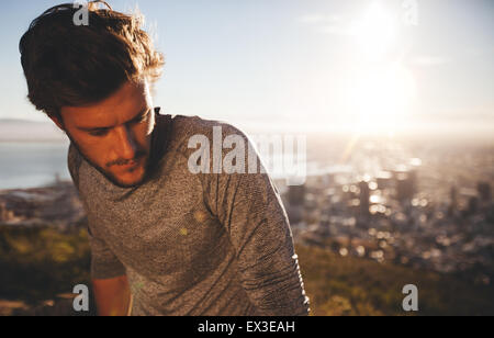 Gros plan du jeune homme se reposant après l'exécution de l'entraînement. Runner à l'extérieur avec la lumière du soleil. Détente à l'athlète af Banque D'Images