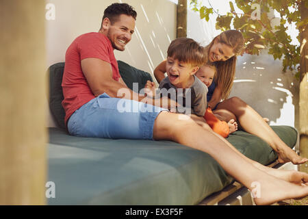 Happy Family sitting ensemble dans l'arrière-cour, d'avoir du plaisir. Père et mère jouant avec leurs enfants tout en restant assis dans le patio. Banque D'Images