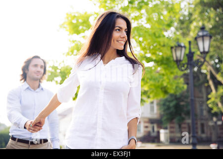 Happy woman holding la main de l'homme et le conduisant à l'extérieur Banque D'Images