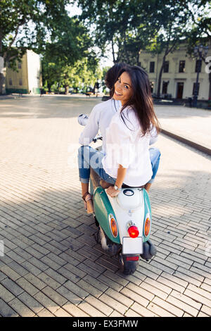 Vue arrière portrait of a happy couple riding sur le scooter en ville Banque D'Images