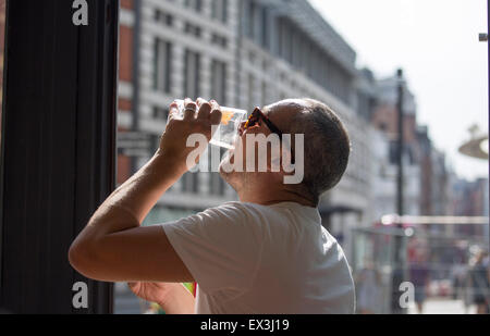 L'homme dans un pub boire une pinte de bière blonde et de contrôler son téléphone mobile Banque D'Images
