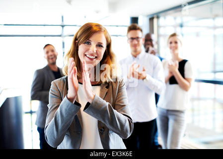 Jeune femme blanche directrice debout devant des collègues des mains et souriant Banque D'Images