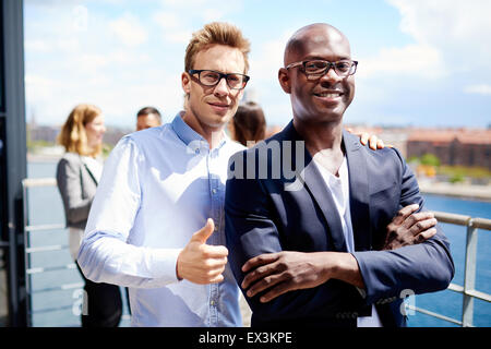 Collègue masculin blanc debout avec la main sur l'épaule de collègue et faire un Thumbs up sign Banque D'Images