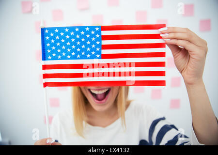 Cheerful woman couvrant ses yeux avec drapeau USA Banque D'Images