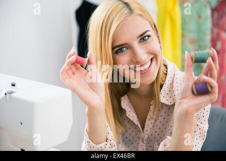 Female deisgner holding thread and looking at camera Banque D'Images