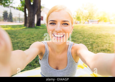 POrtrait of a smiling young girl making photo selfies dans park Banque D'Images