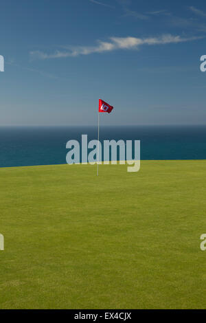 Golf rouge sur le drapeau vert avec mer bleue et le ciel derrière. Banque D'Images