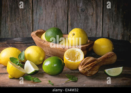 Tas d'ensemble et les tranches de citrons et limes bol en bois d'agrumes et de l'aléseur fond de bois Banque D'Images