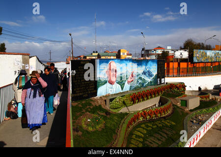 La Paz, Bolivie, le 6 juillet 2015. Une dame Aymara passe devant une murale peinte récemment dans La Ceja, El Alto du Pape François avec une prière pour sa bonne arrivée en Bolivie. Le pape François se rendra à El Alto et La Paz le 8 juillet au cours de sa 3 journée à la Bolivie. Banque D'Images