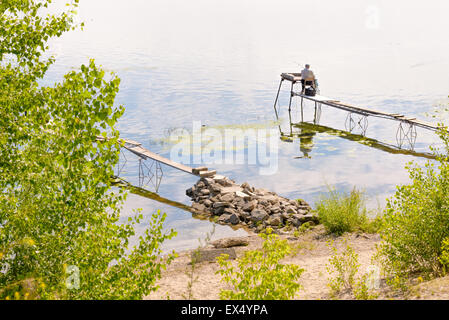 Kiev, Ukraine - 30 juin 2015 : un pêcheur sur un ponton est en attente d'attraper un gros poisson sur le fleuve Dniepr. Banque D'Images