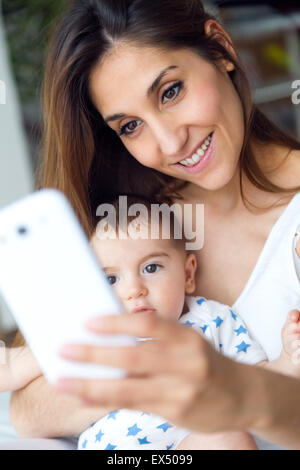 Portrait de la belle mère et l'enfant de prendre une à la maison selfies. Banque D'Images