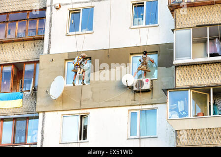 Kiev, Ukraine - 30 juin 2015 : Façade plâtriers construire l'isolation thermique externe d'un appartement assis sur leur swing Banque D'Images