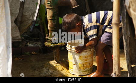 Chaud en Inde. Petit garçon lui-même refeshing avec de l'eau froide du puits. Banque D'Images