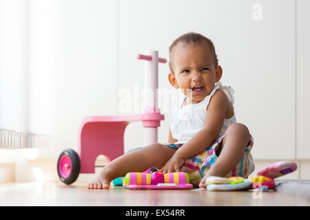 Portrait of little African American petite fille assise sur le sol et à jouer - les noirs Banque D'Images