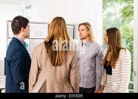 Businesspeople looking at bulletin board in office Banque D'Images