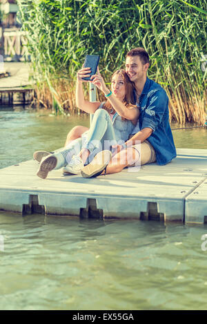 Couple amoureux assis sur la jetée, selfies Banque D'Images