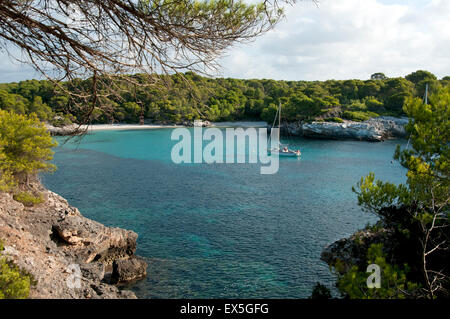 Un bateau à la location dans le calme des eaux turquoise du Cala Turqueta sur l'île de Minorque espagne Banque D'Images