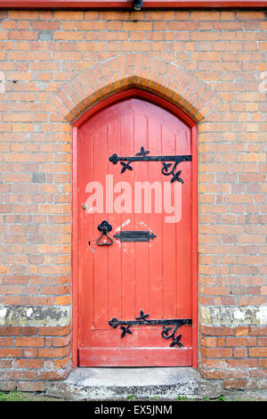 Vieille porte en bois peint en rouge avec des meubles en fer forgé. Banque D'Images