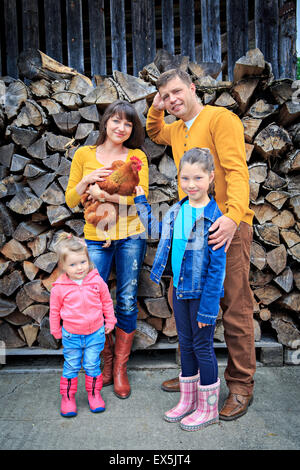 Une famille agricole avec une poule en face de la ferme Banque D'Images