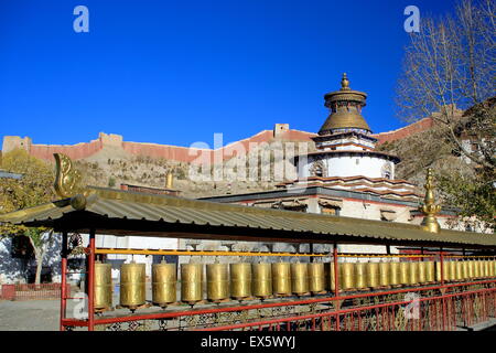 Rangée de moulins à prière en laiton à l'intérieur du monastère de Pelkhor Chode-bouddhiste avec le Kumbum ou Tashigomang s'avançant sur la pagode. Tibet Banque D'Images