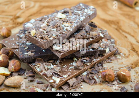 Chocolat foncé empilées sur une table saupoudrée de cacao baskcgound avec les noix et amandes Banque D'Images