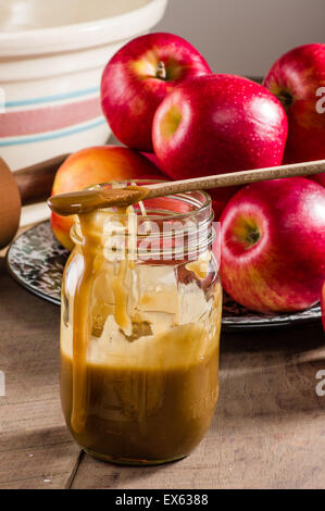 Cuillère à pot Mason et sauce au caramel et pommes rouges Banque D'Images