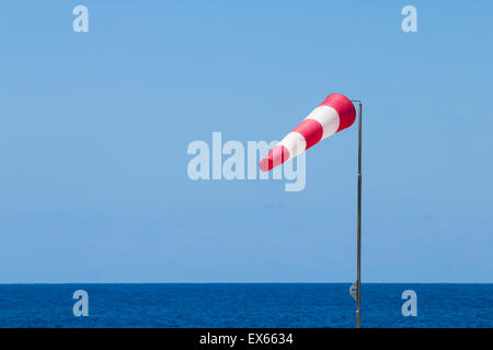 Manche à vent rouge et blanc sur la plage Banque D'Images
