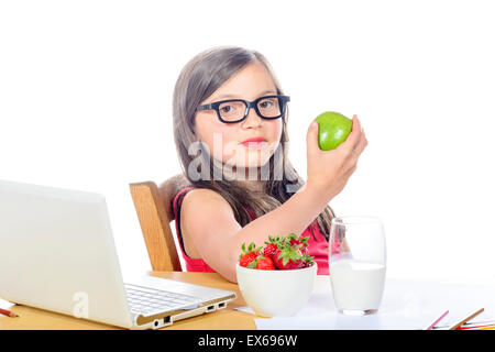 Une jolie petite fille aux cheveux longs mange une pomme on white Banque D'Images