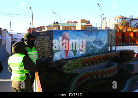 El Alto, Bolivie, 8th juillet 2015. Les policiers patrouillent la passerelle à côté d'une fresque du Pape François à la CEJA qui a été dépeinte en rouge la veille de son arrivée à El Alto au début de sa visite de 3 jours en Bolivie. Le Pape doit arriver aujourd'hui, alors que beaucoup de gens sont impatients de sa visite un peu de non catholiques sont contre lui et le montant de l'argent est dépensé sur lui. Pour certains peuples autochtones, l'église catholique est encore associée à la conquête et à l'occupation espagnoles des Amériques et à la répression de leurs croyances. Credit: James Brunker / Alamy Live News Banque D'Images