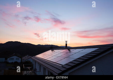 Construit en panneaux solaires sur un toit de maison à Ambleside, Lake District, UK, au coucher du soleil. Banque D'Images