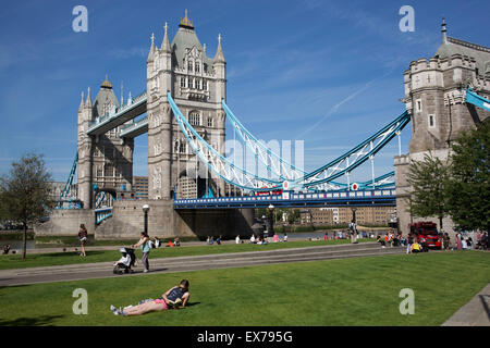 L'été à Londres, Angleterre, Royaume-Uni. Femme lisant près de Tower Bridge à Potters Fields Park. Ce nouvel espace vert est populaire auprès des touristes et d'autres à venir pour un été reste avec ce grand établissement emblématique comme toile de fond. Banque D'Images