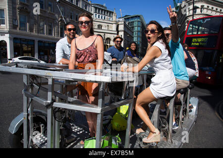 L'été à Londres, Angleterre, Royaume-Uni. Le Pedibus est un cycle de 8 places avec bar. Groupe d'amis profitant d'une visite en bus de la pédale. Le Pedibus a London Tours sont un moyen amusant pour des groupes de personnes de profiter des sites, tout en célébrant et en consommant de l'alcool. Souvent pour les anniversaires, les enterrements de vie de garçon ou etc. Banque D'Images