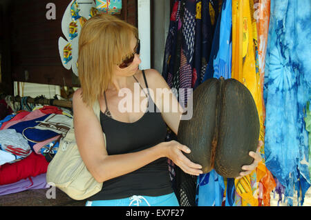 Une femme tenant un coco de mer, de la mer, noix de coco, noix de coco double amour, coco fresse, Seychelles ou l'écrou (Lodoicea maldivica) Mahe Banque D'Images