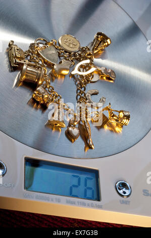 VENTE DE POIDS DE FERRAILLE D'OR VENDRE vieux bracelet de charme en or sur la machine de pesage numérique affichant 26 grammes de poids Banque D'Images