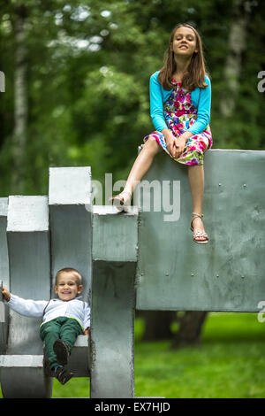 Petit garçon avec sa sœur aînée sur l'aire de jeux dans le parc. Banque D'Images